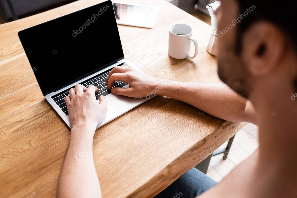 cropped view of male freelancer working on laptop with blank screen