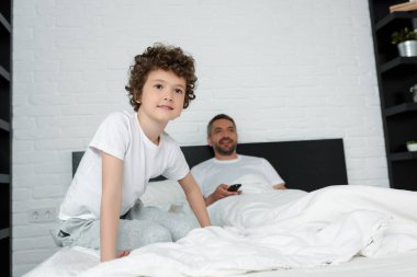 Sevimli bir çocuğun babasının yanında oturup uzaktan kumandayı tutmasının seçici odağı. 