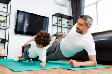 Yakışıklı baba ve yakışıklı oğul spor paspasları üzerinde çalışıyor. 