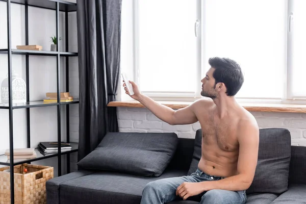 Sexy Young Man Remote Controller Adjusting Temperature Air Conditioner Home — Stock Photo, Image