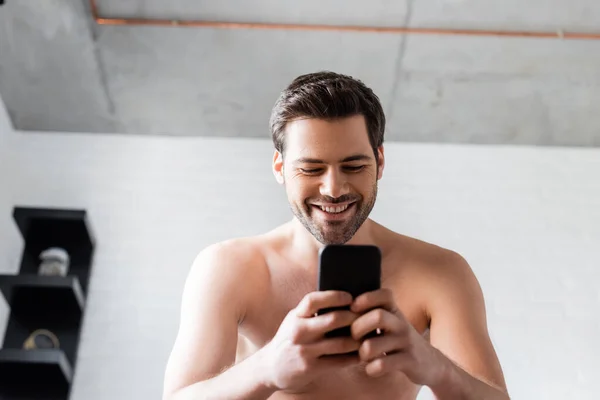 Sonriente Joven Hombre Sin Camisa Usando Teléfono Inteligente Casa —  Fotos de Stock