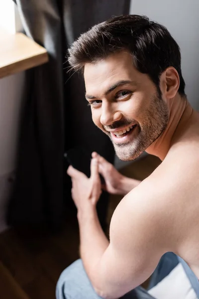 Uśmiechnięty Mężczyzna Bez Koszulki Pomocą Smartfona Pustym Ekranem Domu — Zdjęcie stockowe