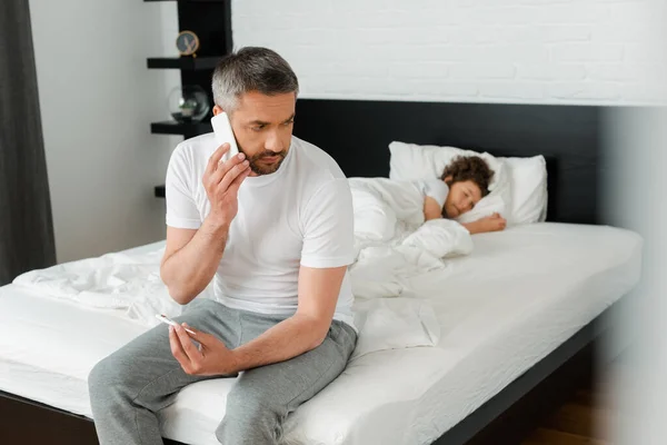 Selektivt Fokus För Man Med Digital Termometer Talar Smartphone Nära — Stockfoto