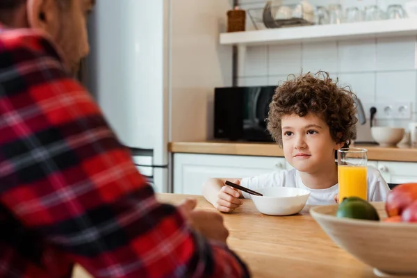 有选择地专注于卷曲的男孩看着爸爸近好吃的早餐放在桌上 — 图库照片