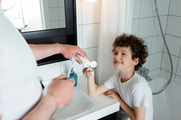 Selective Focus Father Holding Toothpaste Toothbrush Cheerful Curly Son — Stock Photo, Image