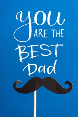 Decorative black paper crafted fake mustache on white stick isolated on blue, you are the best dad illustration clipart