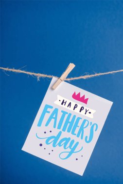 White greeting card with happy fathers day illustration hanging on rope with clothespins isolated on blue clipart