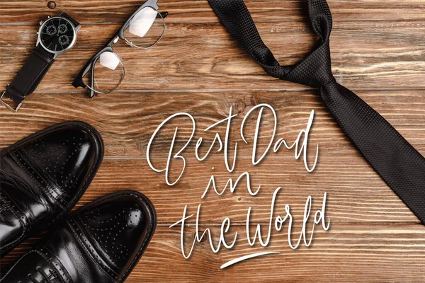 Top view of mens black shoes, tie, wristwatch and glasses on wooden background, best dad in the world illustration