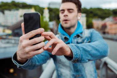 Şehir caddesinde akıllı telefonla fotoğraf çeken adamın seçici odak noktası 