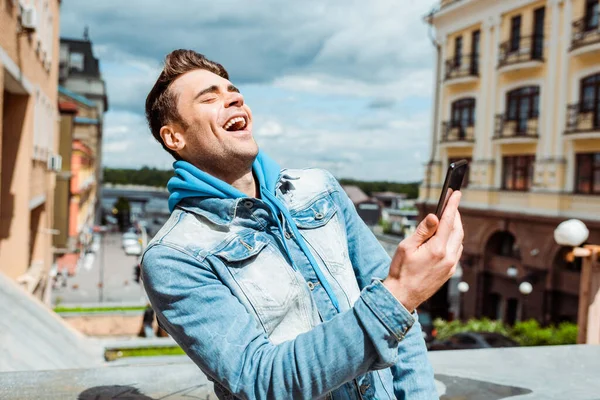 Hombre Guapo Riendo Mientras Sostiene Teléfono Inteligente Calle Urbana — Foto de Stock