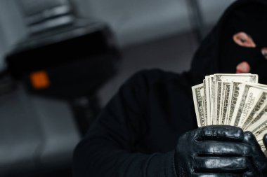 Elinde dolar tutan deri eldivenli hırsızın seçici odak noktası. 