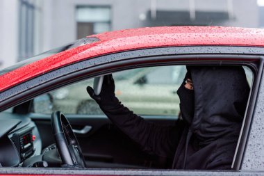 Arabada otururken aynayı ayarlayan hırsızın yan görüntüsü 