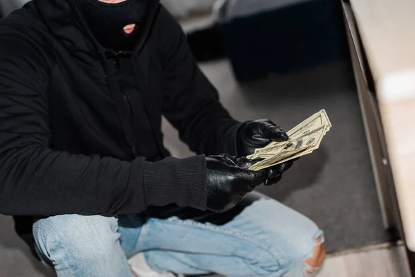盗窃者在盗窃案中戴口罩和皮手套并持有美元的选择性焦点 — 图库照片