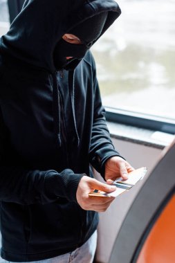 Kar maskeli hırsızın seçici odak noktası ATM 'nin yanında kredi kartı tutması. 