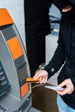 Kredi kartı tutarken ATM kullanan kar maskeli hırsızın seçici odak noktası 