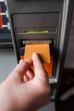 Otomatik veznedar makinesi kullanırken kredi kartı tutan adamın kırpılmış görüntüsü