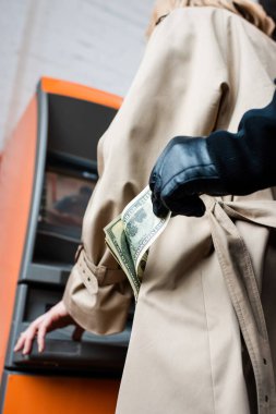 Deri eldivenli soyguncunun ATM 'nin yanındaki kadın ceketinin cebinden dolar banknotları alırken görülmüş. 