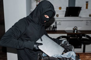 Kar maskeli bir soyguncu hırsızlık sırasında bilgisayarı çantaya koymuş. 