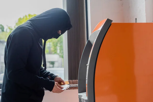 Seitenansicht Des Räubers Maske Mit Kreditkarten Der Nähe Von Geldautomaten — Stockfoto