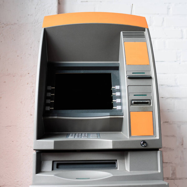 ATM with blank screen near white brick wall
