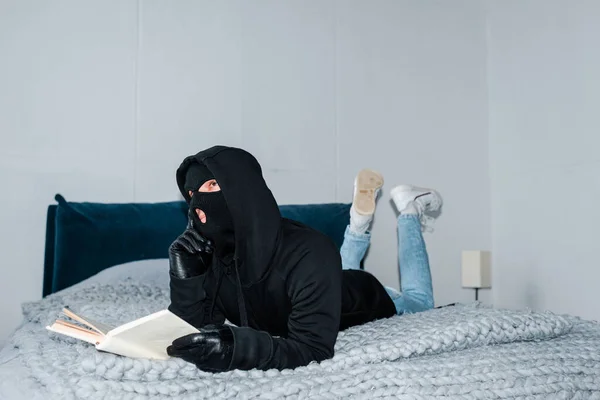 Pensive Robber Balaclava Holding Book While Lying Bed — Stok Foto