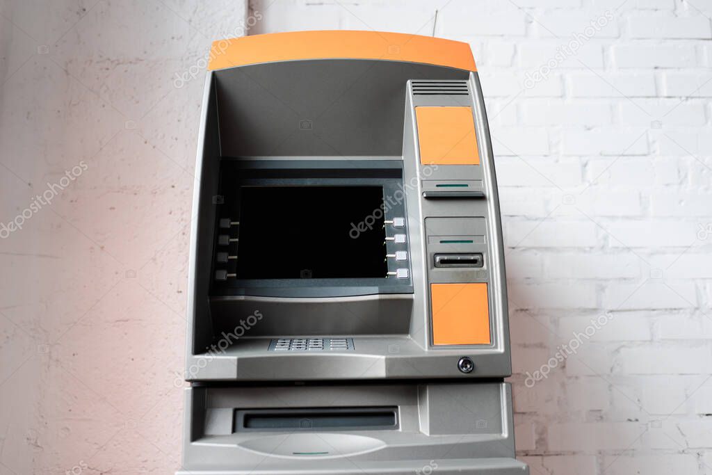 Automated teller machine with blank screen near white brick wall 