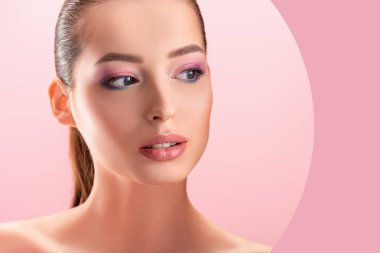 Güzel, çıplak bir kadın, parlak makyajlı. Pembe üzerine izole edilmiş kağıttan bir delikten bakıyor.