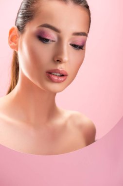 Parlak makyajlı güzel çıplak bir kadın portresi Pembe bir deliğe bakıyor.