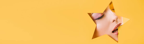портрет красивой женщины с блестящим макияжем в бумажной форме звезды отверстие с закрытыми глазами и открытым ртом изолированы на желтый, панорамный снимок
