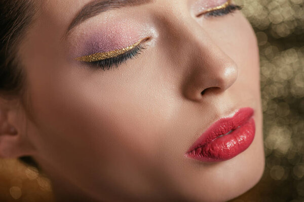 close up view of beautiful woman with shiny makeup and closed eyes