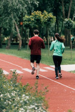 Selective focus of couple running on running path in park  clipart