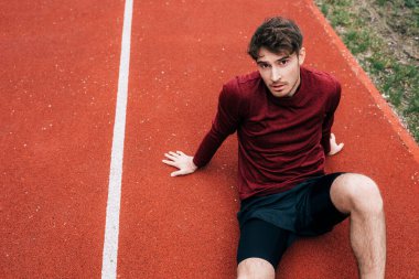 Yakışıklı sporcu parkta koşarken kameraya bakıyor. 