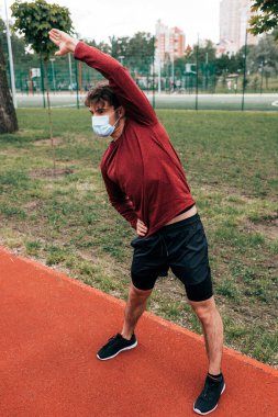 Sağlık maskeli sporcu parkta koşu parkurunda çalışıyor. 