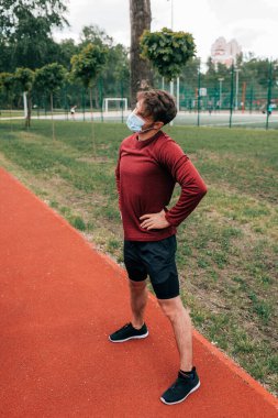 Parkta kalça eğitimi almış tıbbi maskeli bir sporcu. 