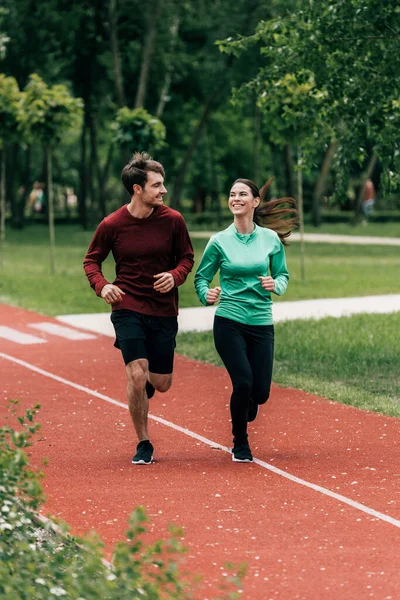 女运动员在公园慢跑时向男朋友微笑的选择性焦点 — 图库照片