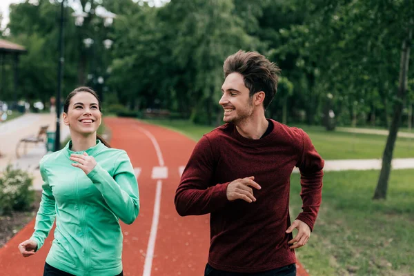 Usmívající Muž Při Pohledu Pozitivní Přítelkyně Při Jogging Parku — Stock fotografie