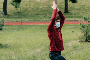 Tıp maskeli sporcu parkta egzersiz yapıyor. 