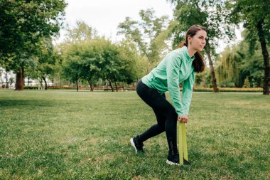 Parkta direniş bandı ile genç sporcu kadın eğitiminin yan görüntüsü 