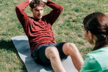 Parktaki spor minderinde karın kası yapan yakışıklı adamın seçici odak noktası. 