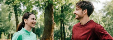 Parkta erkek arkadaşına bakan gülümseyen sporcu kadının panoramik mahsulü. 