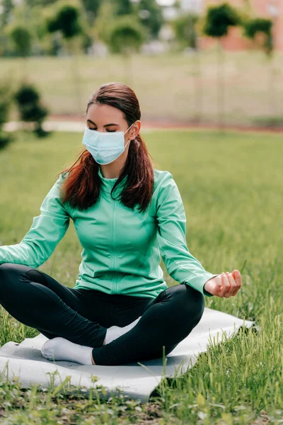 Enfoque Selectivo Mujer Joven Máscara Médica Meditando Esterilla Fitness Parque —  Fotos de Stock