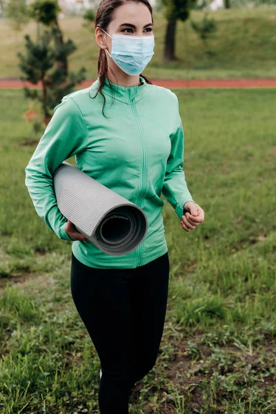 Jovem Desportista Máscara Médica Segurando Tapete Fitness Enquanto Caminhava Parque — Fotografia de Stock