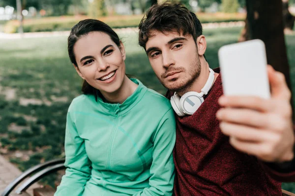 Selective Focus Smiling Sportswoman Taking Selfie Smartphone Handsome Boyfriend Bench — Stock Photo, Image