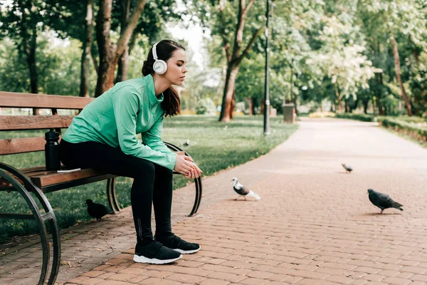 Sidovy Idrottskvinna Hörlurar Sitter Nära Sportflaska Och Smartphone Bänk Parken — Stockfoto