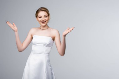 Beyaz gelinlik içindeki neşeli gelin gri renkte izole edilmiş el kol hareketi yapıyor. 