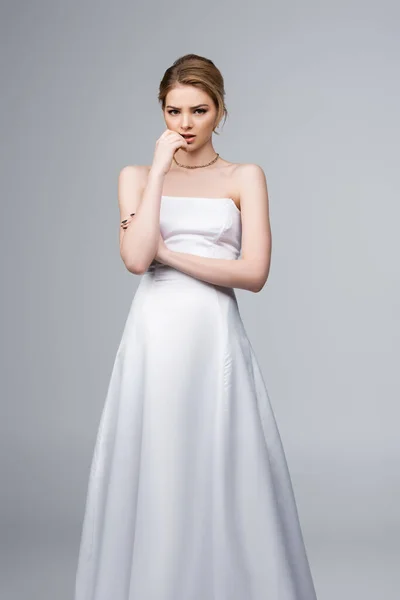 白いウェディングドレスの心配花嫁は灰色で隔離された顔に触れる — ストック写真