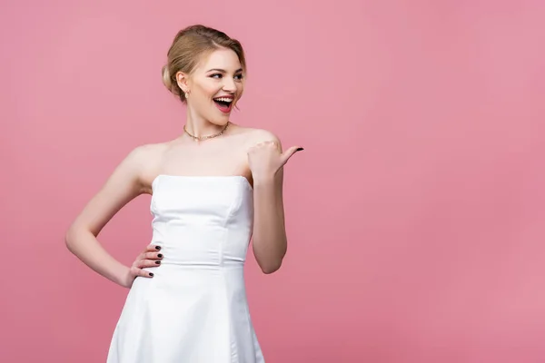 Upphetsad Brud Vit Bröllopsklänning Pekar Med Tumme Isolerad Rosa — Stockfoto