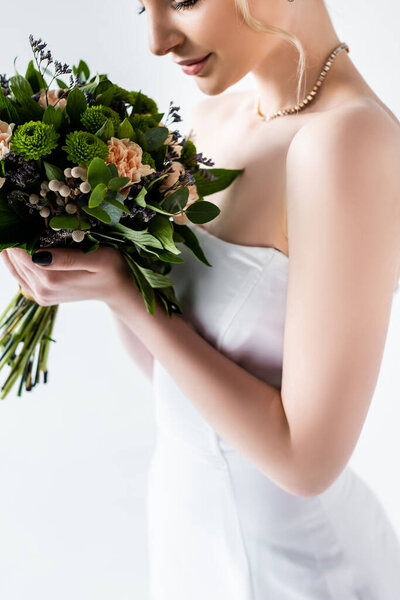 cropped view of bride in elegant wedding dress holding flowers isolated on white 