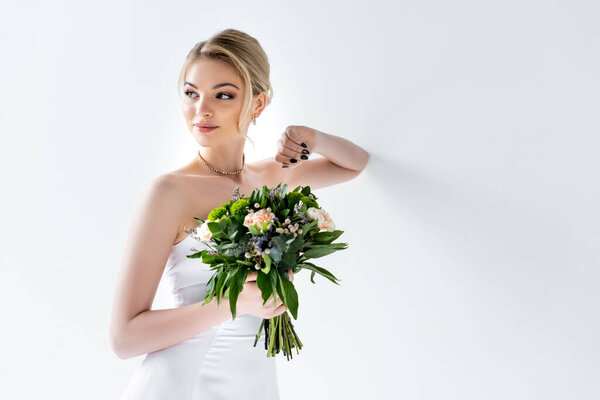 beautiful bride in elegant wedding dress holding flowers on white 