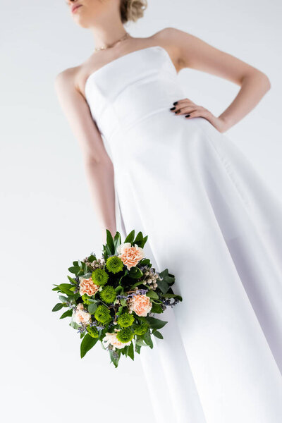 cropped view of elegant bride in wedding dress holding flowers isolated on white 